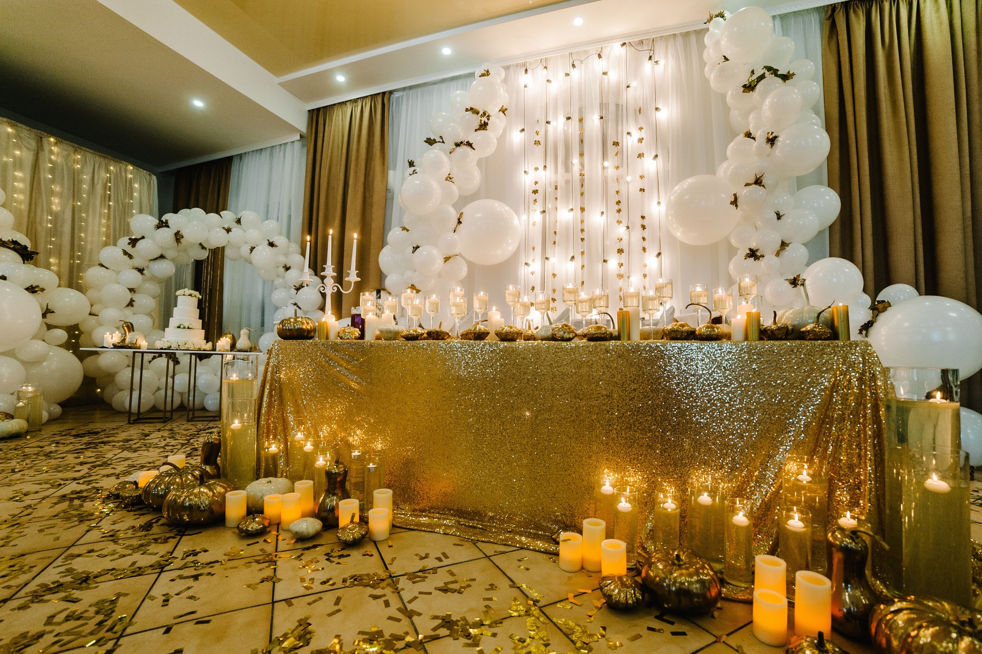 Table setting for wedding. Decorated arch for wedding ceremony. White balloons, candles, autumn leaves and small pumpkins. Autumn location and Halloween decor.